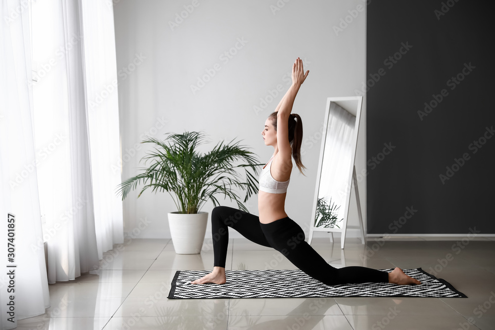 Beautiful young woman practicing yoga at home