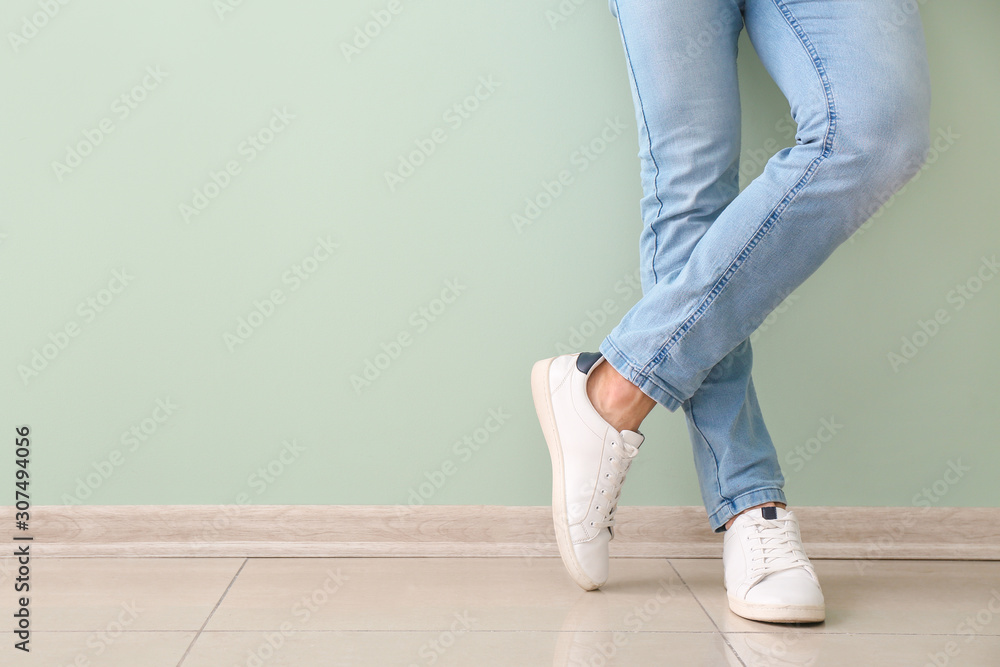 Young man in stylish shoes near color wall