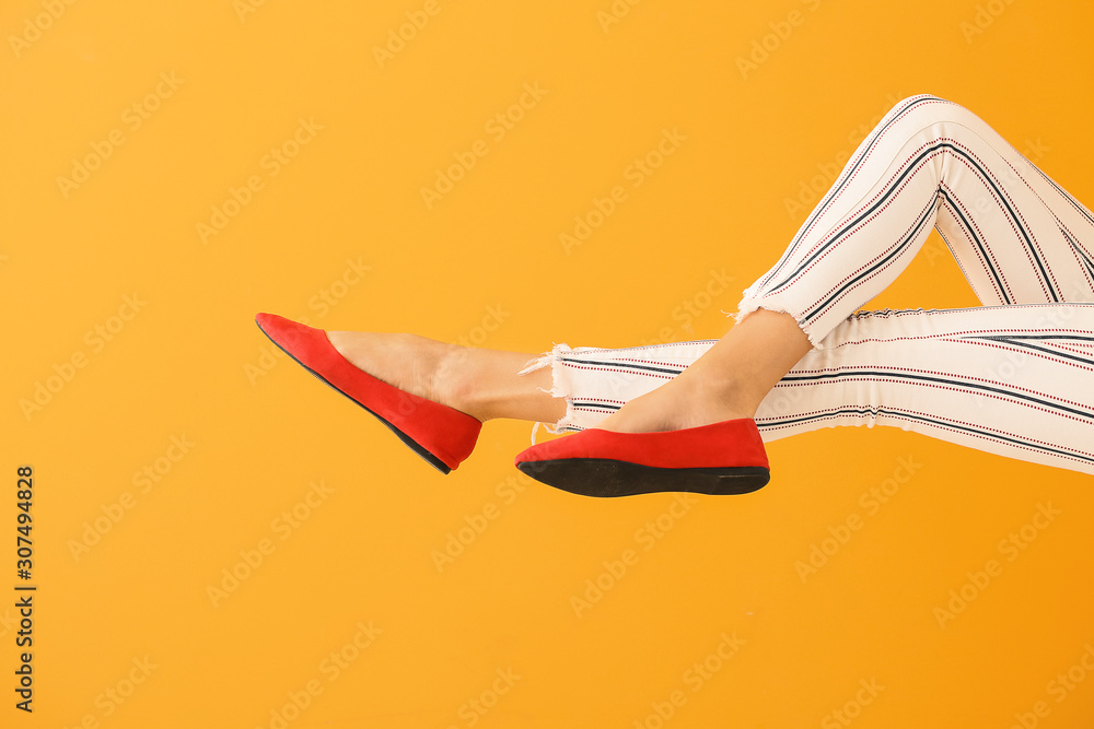 Young woman in stylish shoes on color background