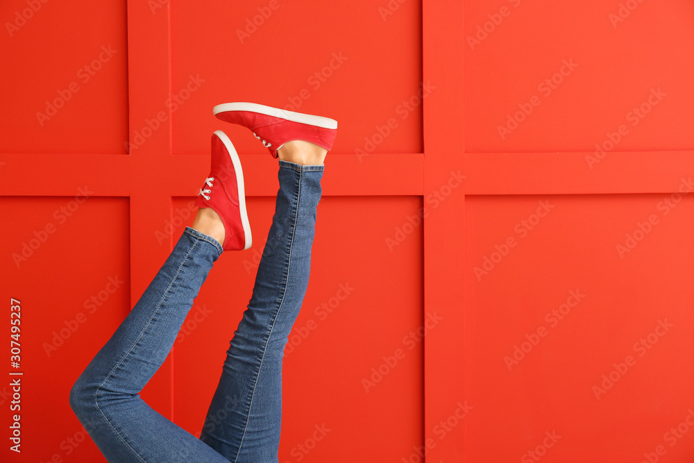 Young woman in stylish shoes on color background