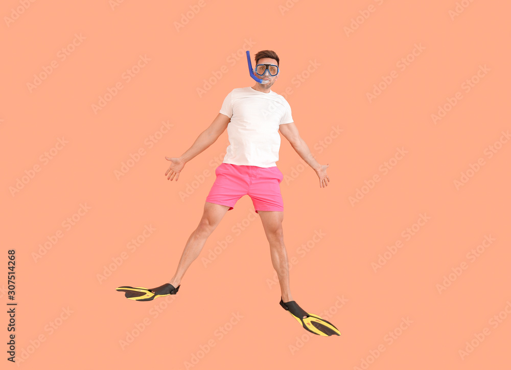 Jumping man in paddles and snorkeling mask on color background