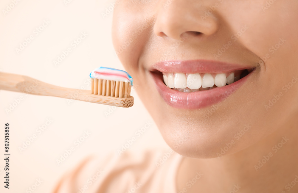 Beautiful young woman with tooth brush on light background, closeup