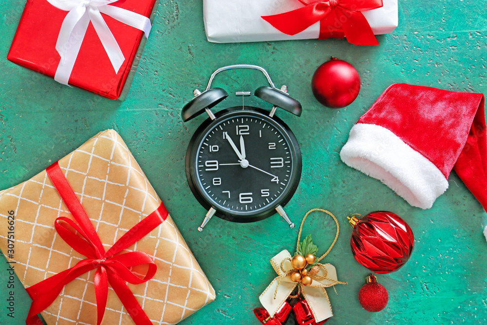 Alarm clock, Santa hat and gifts on color background. Christmas countdown concept