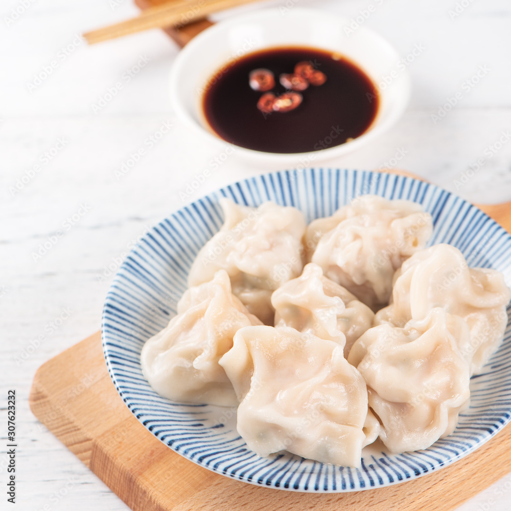 新鲜美味的水煮猪肉饺子，白底饺子，酱油和筷子