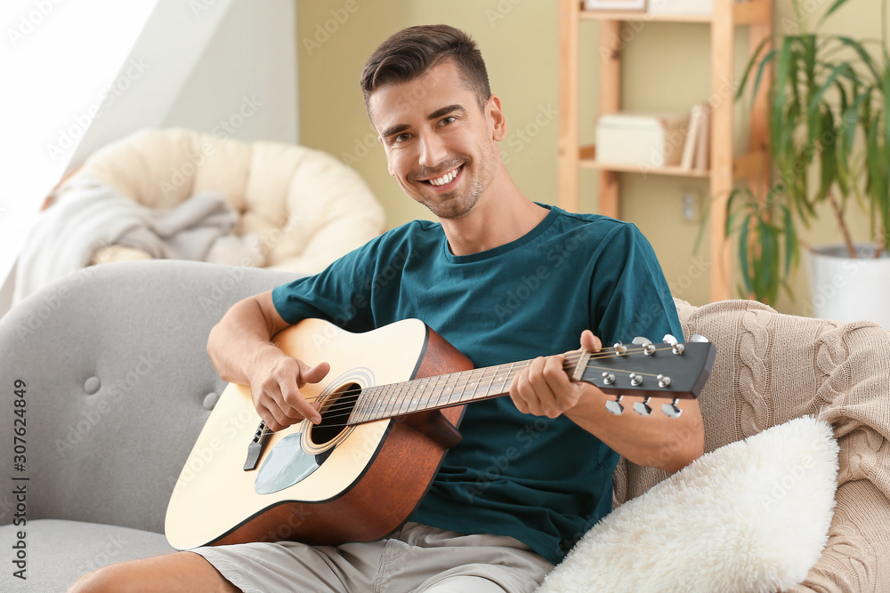 Handsome man playing guitar at home