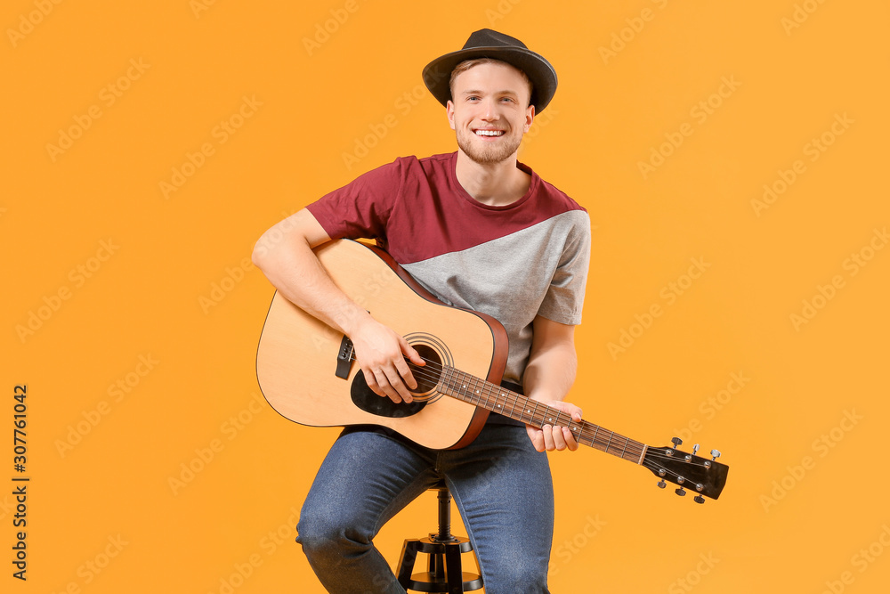 Handsome man playing guitar on color background