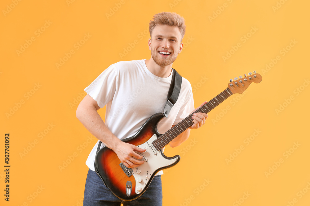 Handsome man playing guitar on color background