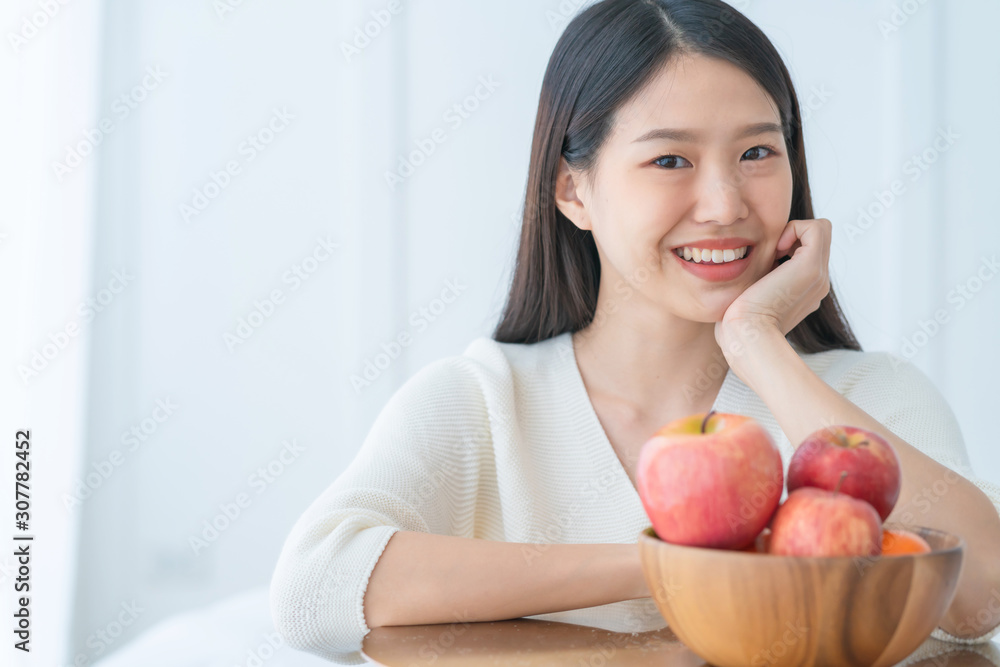 健康饮食理念美丽的亚洲女人微笑着用happine在木碗里展示新鲜的苹果