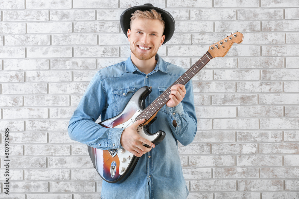 Handsome man with guitar against brick wall