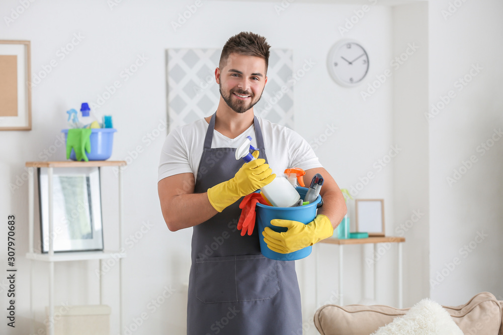 Male janitor with cleaning supplies in room