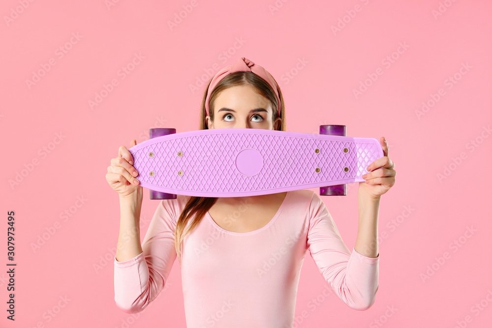 Stylish hipster girl with skateboard on color background