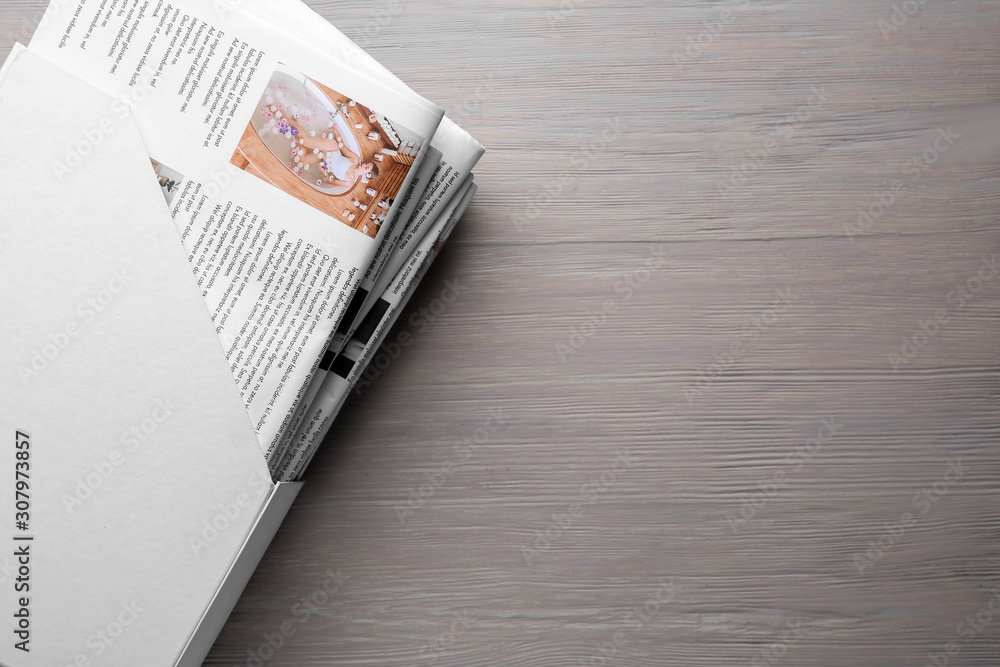 Holder with newspapers on wooden background