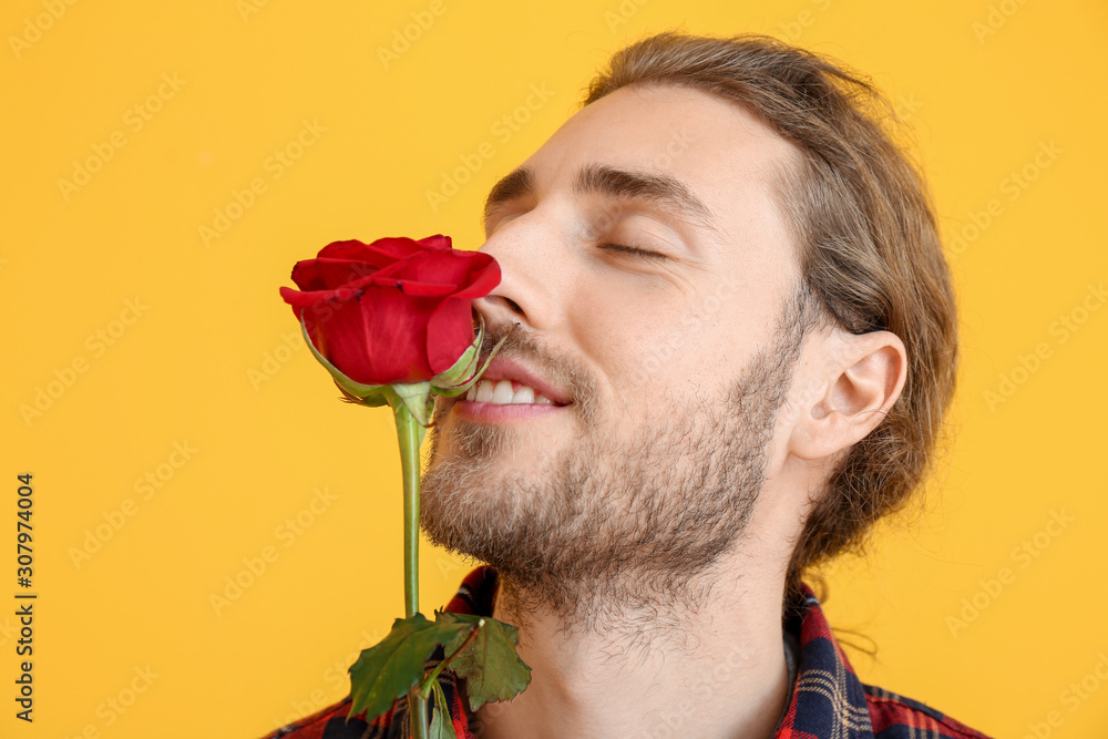 Handsome man with flower on color background. Valentines Day celebration