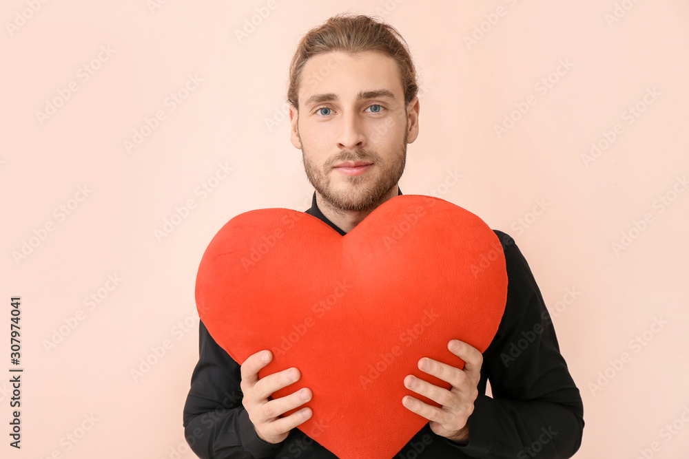 Handsome man with red heart on color background. Valentines Day celebration