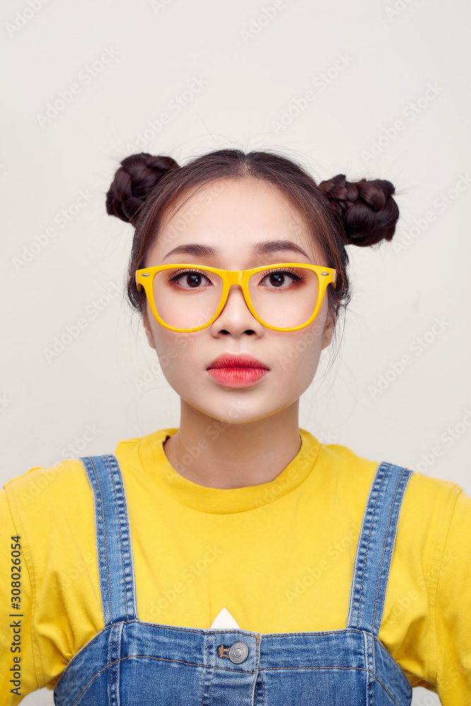 Portrait of nice cute positive pretty cunning Asian girl with two hair-buns, wearing a jeans dungare