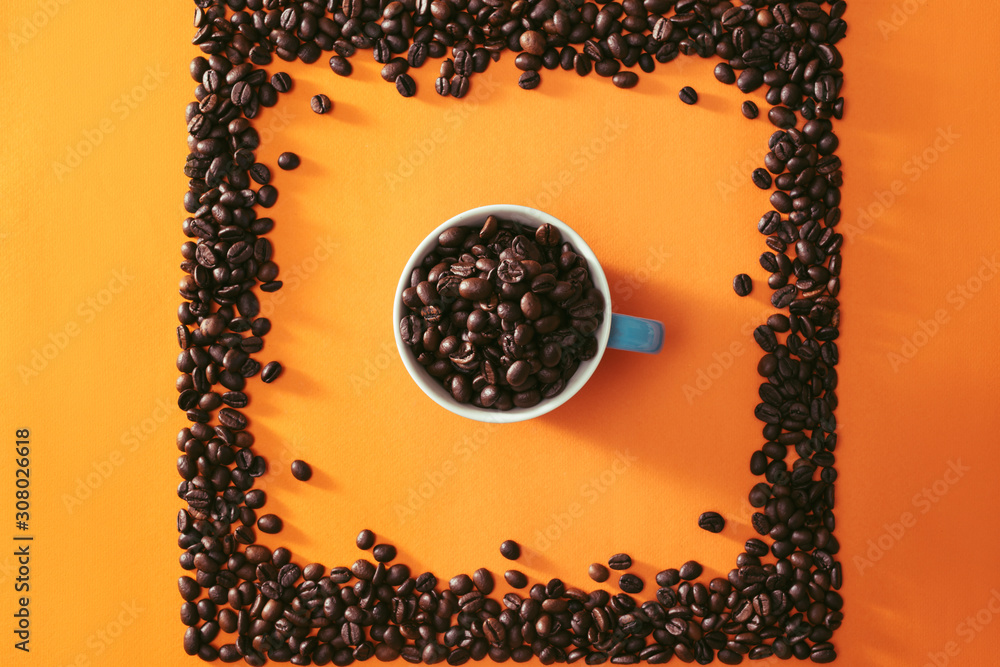 A full cup of coffee beans in the middle of quare shape coffee beans on orange background