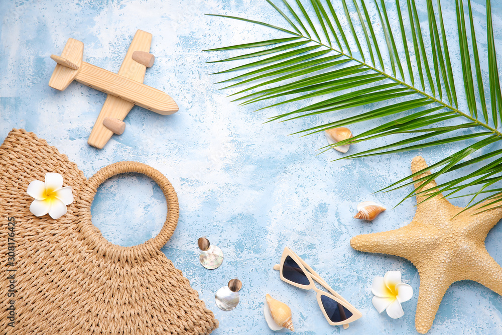 Set of beach accessories with wooden airplane on color background