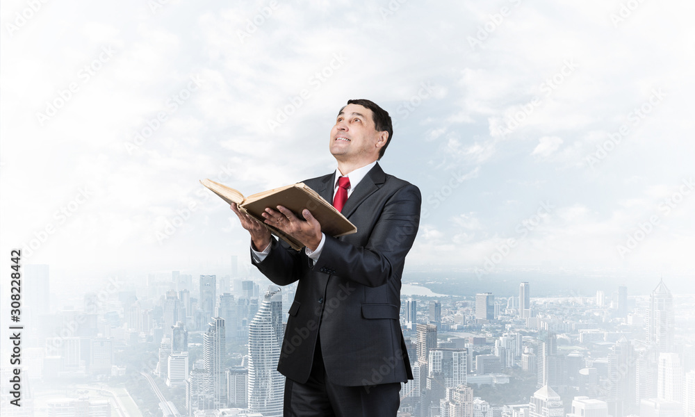 Happy businessman with open book looking up