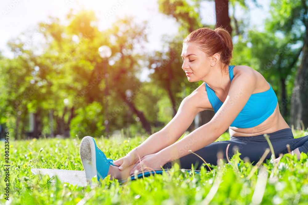 Attractive girl in sportswear doing yoga in park