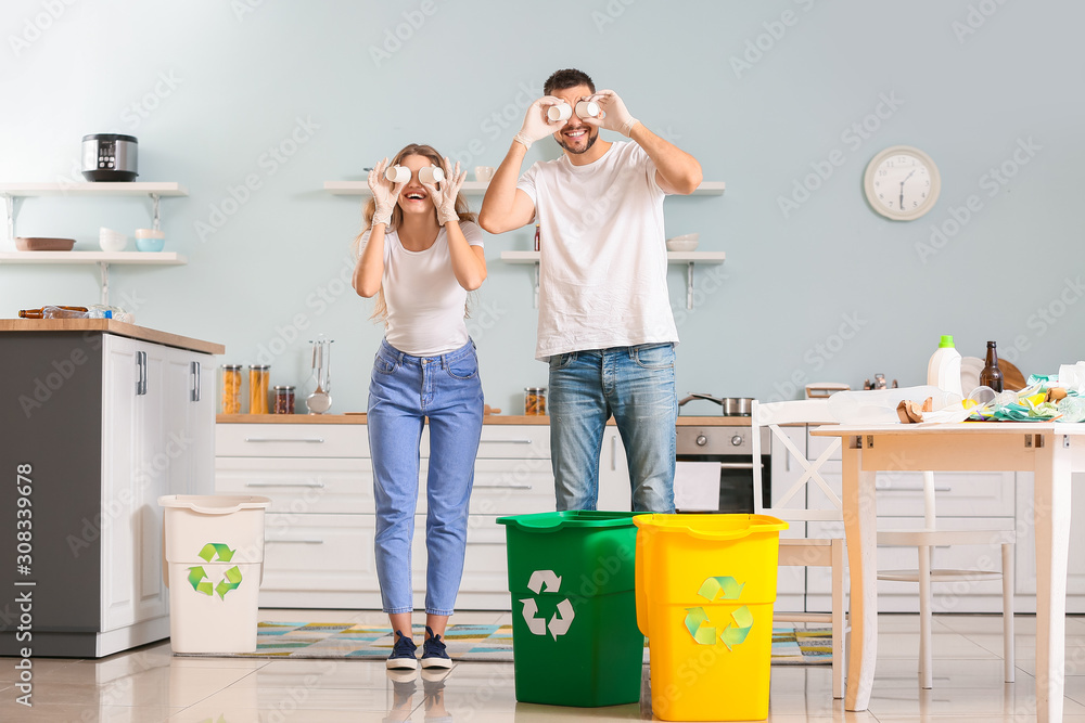 Funny couple sorting garbage at home. Concept of recycling