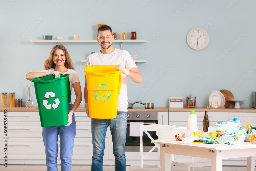 Couple with containers for garbage at home. Concept of recycling