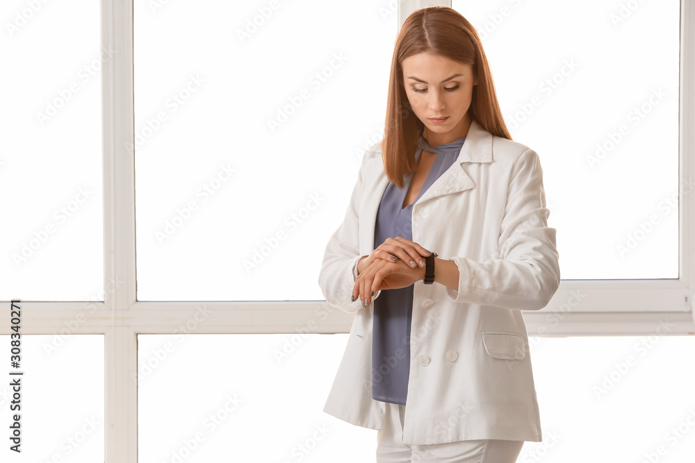 Beautiful young businesswoman looking on her watch in office