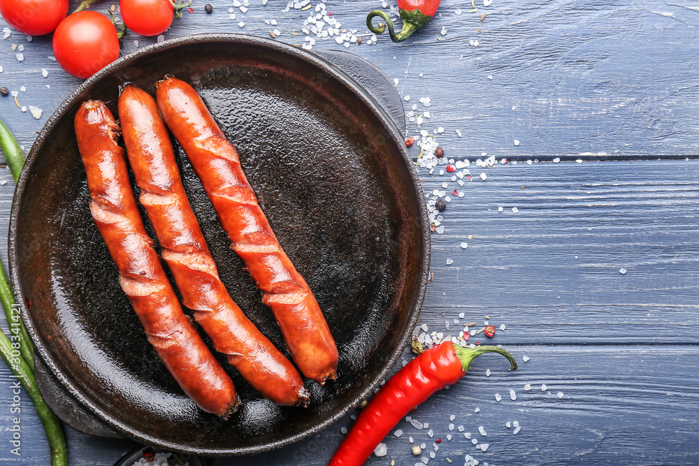 Frying pan with tasty grilled sausages on wooden background