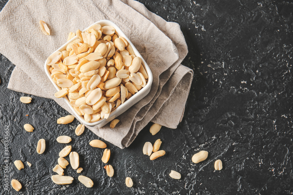 Bowl with peanuts on dark background