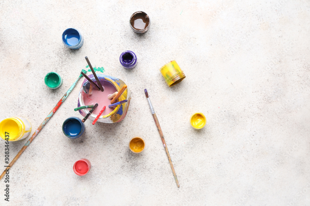 Jar with set of artists brushes and paints on light background