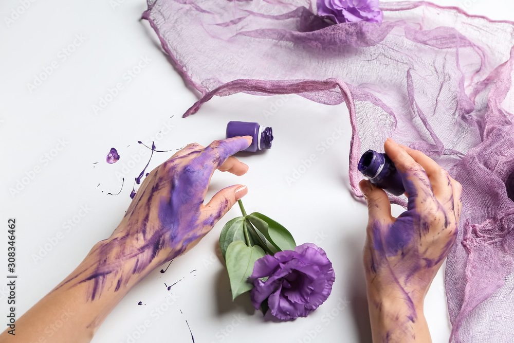 Artists hands in paint, flowers and cloth on white background