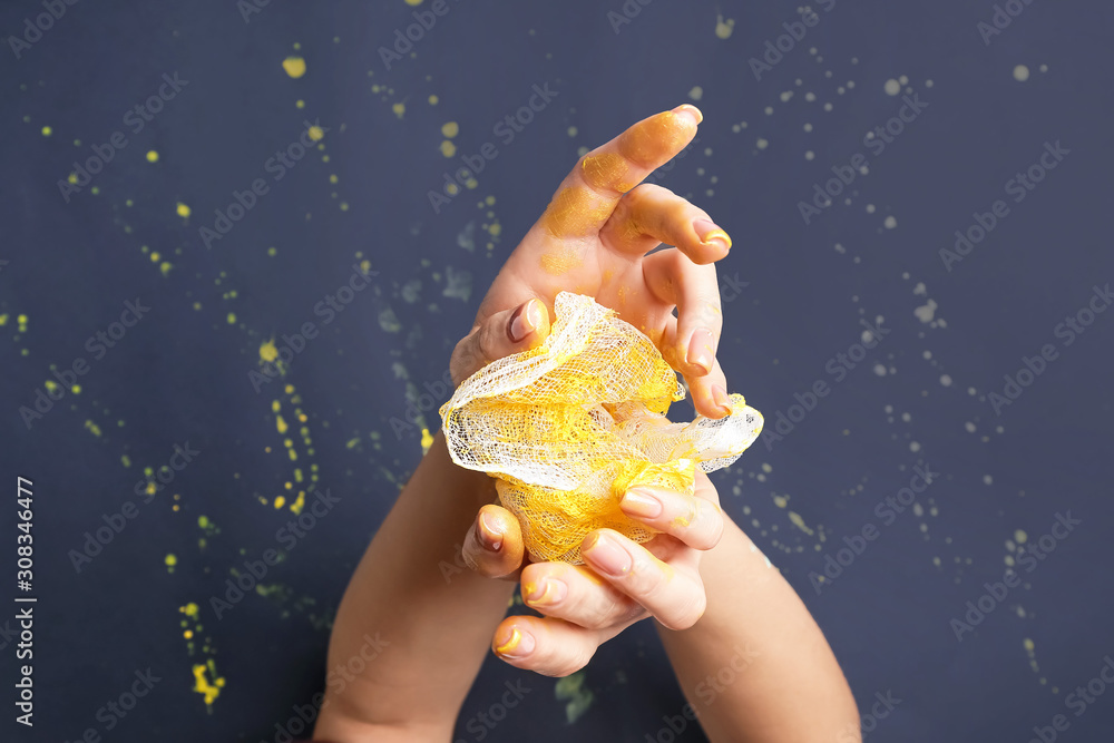 Artist wiping paint from hands against dark background