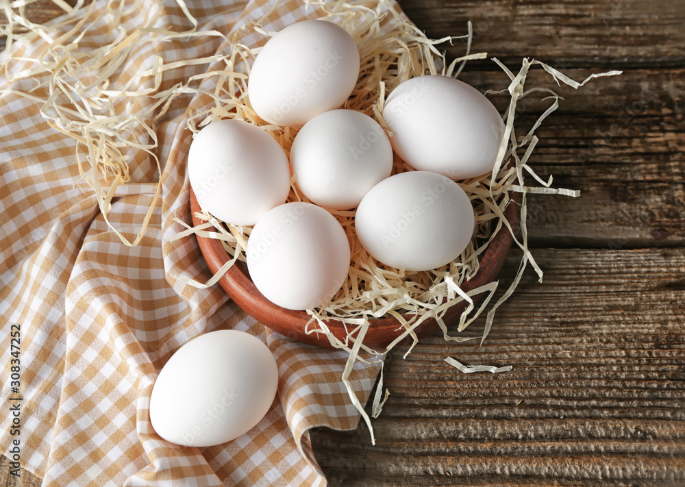 Bowl with fresh raw eggs on table