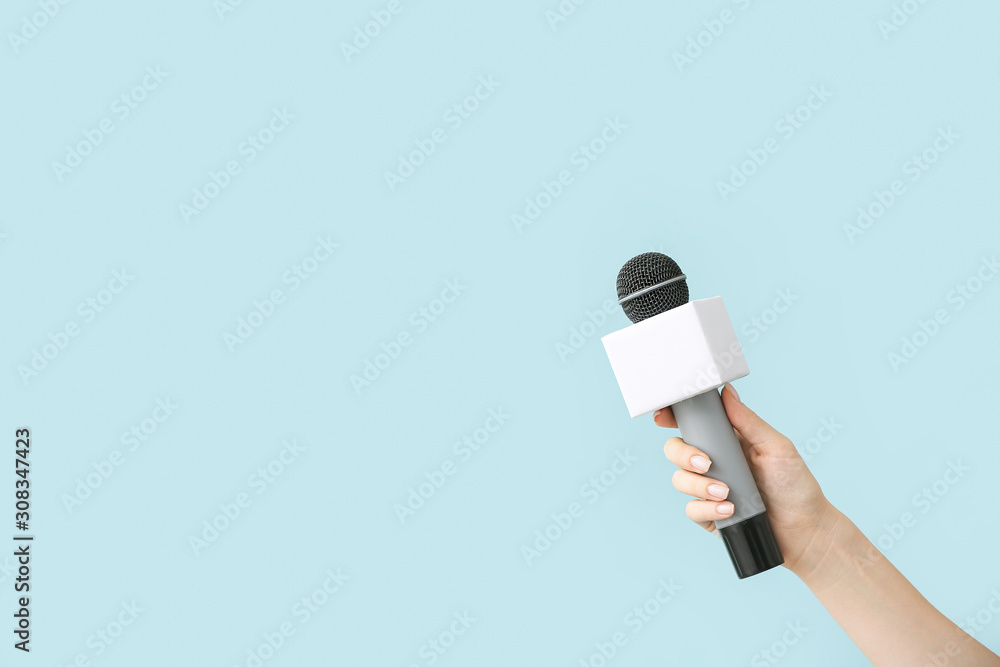 Journalists hand with microphone on color background