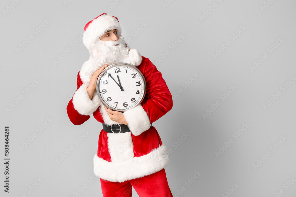 Surprised Santa Claus with clock on light background. Christmas countdown concept