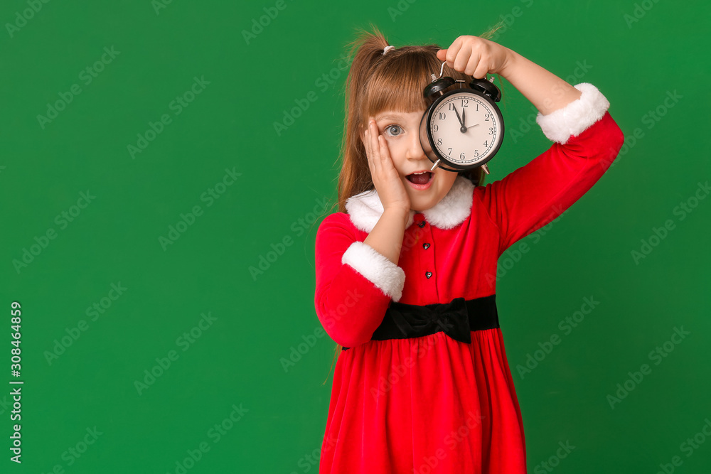 Surprised little girl in Santa costume and with alarm clock on color background. Christmas countdown