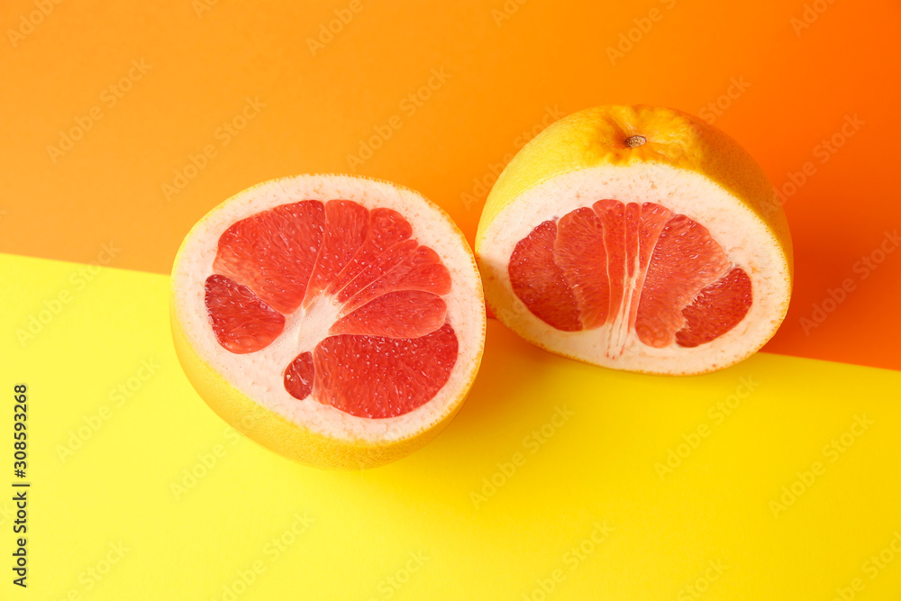 Halves of fresh grapefruit on color background