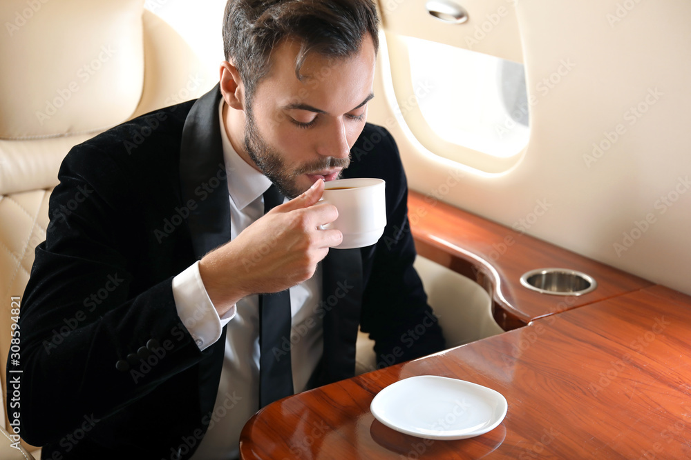 Businessman drinking coffee on board the modern private airplane