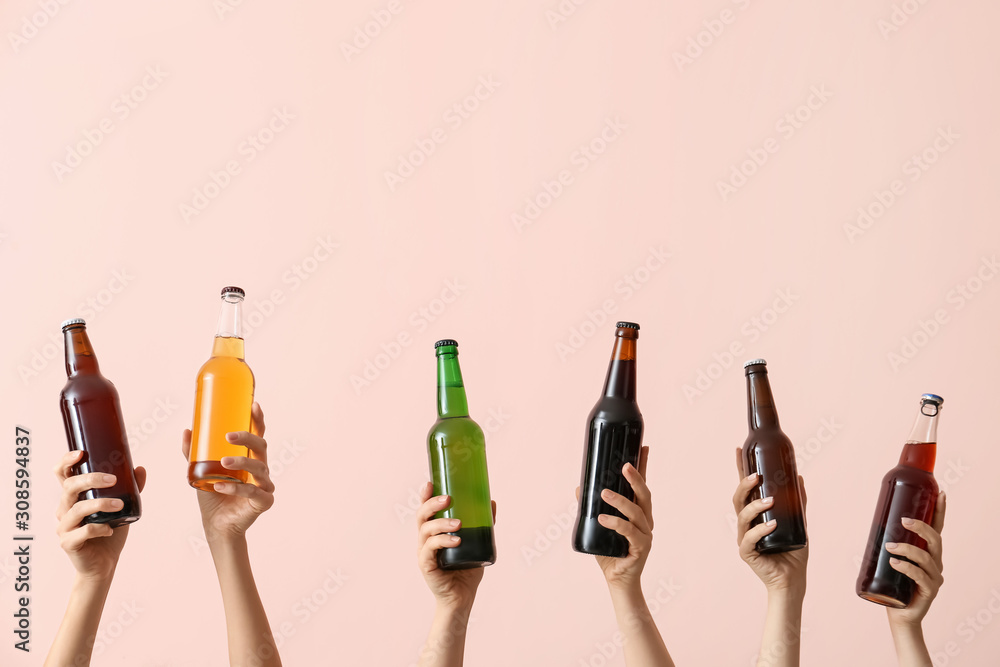 Hands with bottles of beer on color background