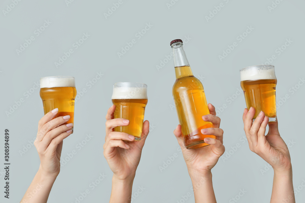 Hands with fresh beer on grey background