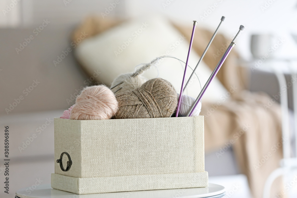 Box with knitting yarns on table