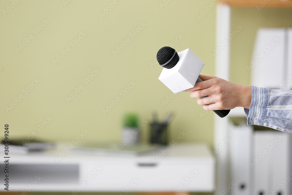 Female journalist with microphone having an interview indoors