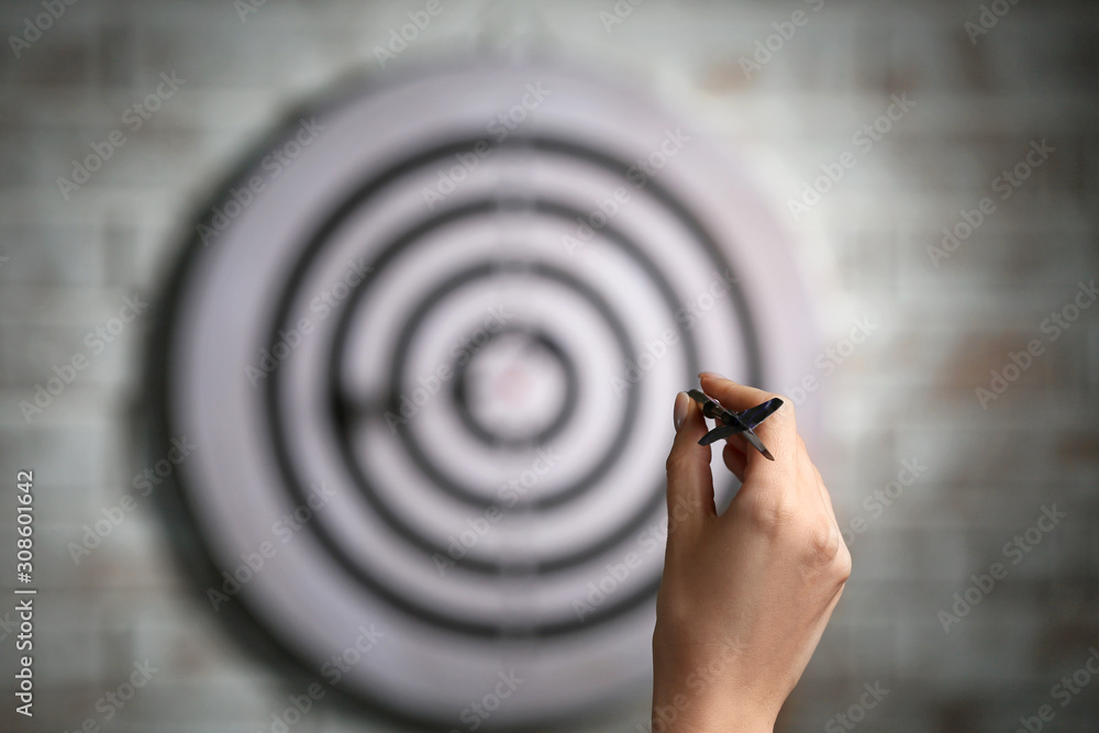 Young woman playing darts indoors