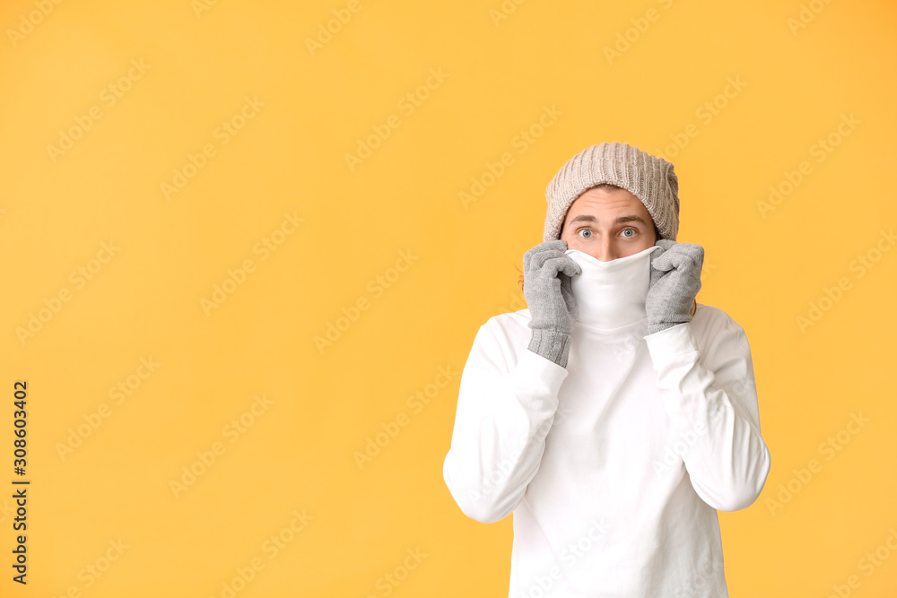 Handsome man in winter clothes on color background