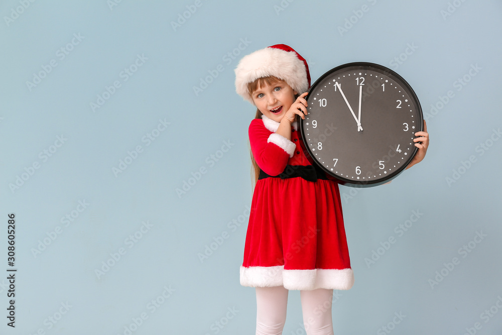 Little girl in Santa costume and with clock on color background. Christmas countdown concept