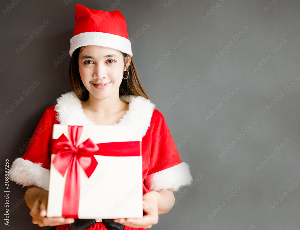 Portrait of young asian caucasian woman girl wearing santa costume and holding gift box on gray back