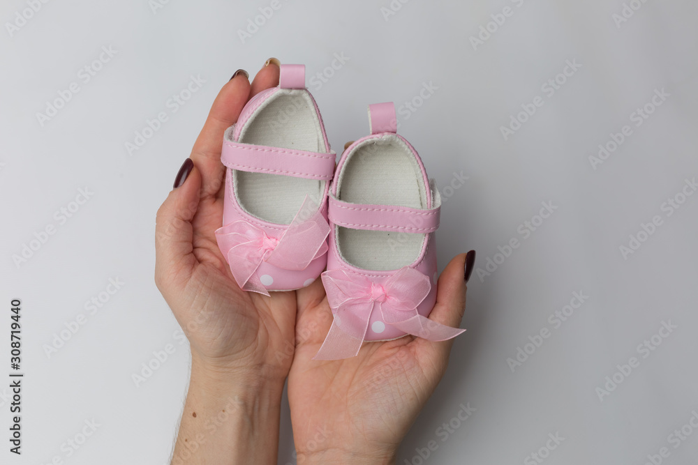 Small pink baby sandals for girl in hands