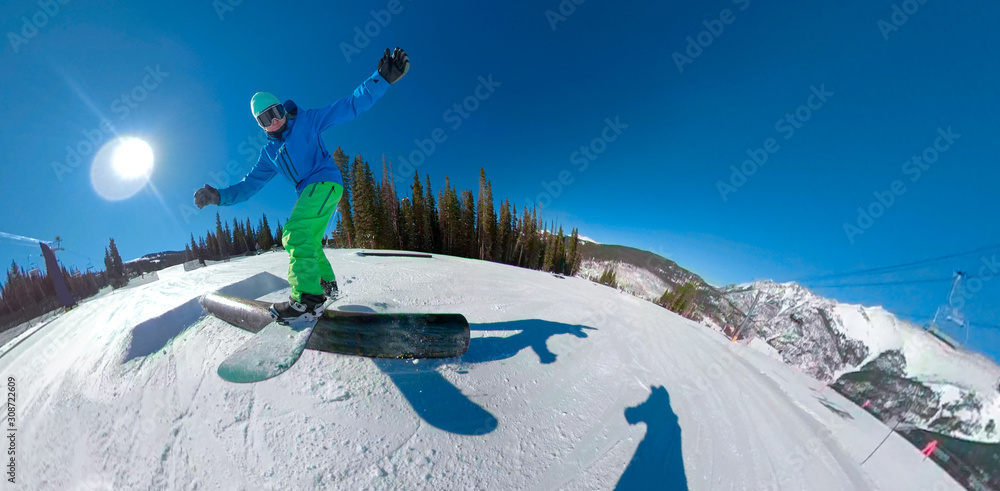 CLOSE UP: Freestyle snowboarder slides along a metal rail in the fun park