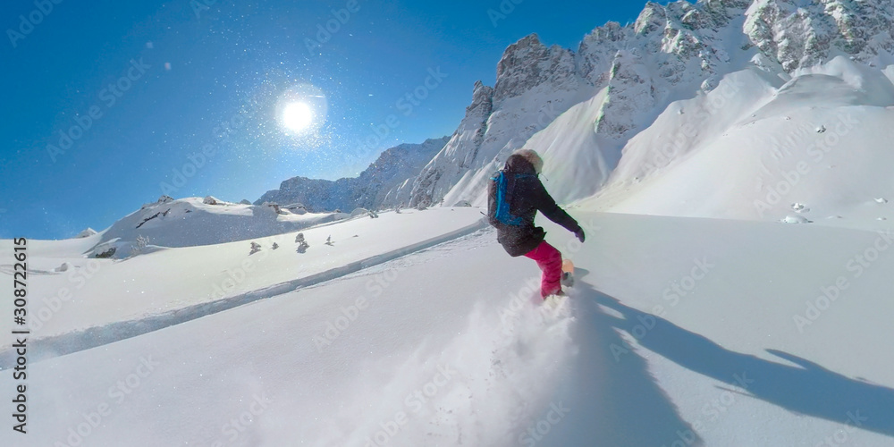 LENS FLARE: Young woman shreds the cold smoke snow while heli boarding in Canada