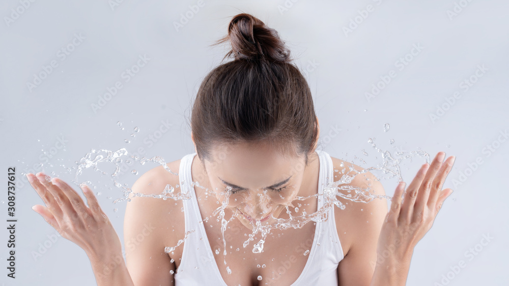 Beautiful woman washing her face in a white background studio