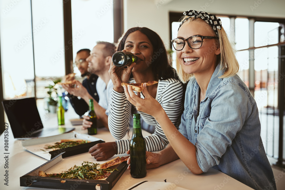 Smiling businesswomen having beers and pizza with colleagues aft